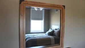 A bedroom with a bed, pillows, a window, and a wooden frame around the window.