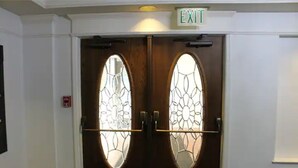 A double wooden door with glass panels and an EXIT sign above.