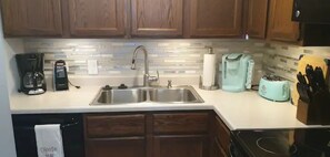 A kitchen with wooden cabinets, a stainless steel sink, a coffee maker, a toaster, and a knife block.