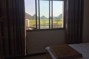 Una habitación con una cama, una ventana con cortinas y vistas a un paisaje montañoso.