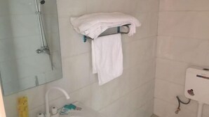 A bathroom with a shower, a sink with toiletries, and a towel rack with towels. - Jinfeng Farmhouse (Luoping)
