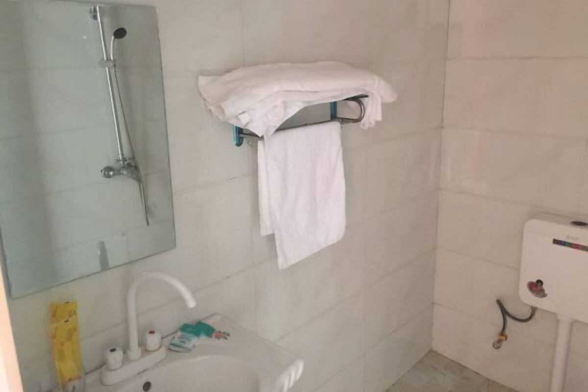A bathroom with a shower, a sink with toiletries, and a towel rack with towels.