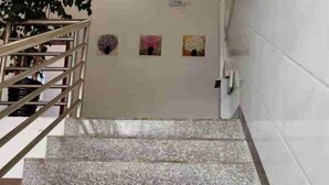 A staircase with a metal railing leading to a door with three floral wall art pieces. - Jinfeng Farmhouse (Luoping)