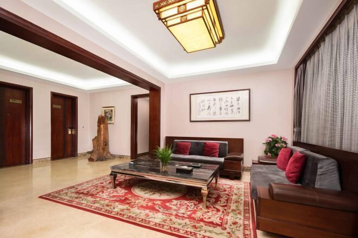 A spacious room with a large coffee table, a sofa, and a red patterned rug.