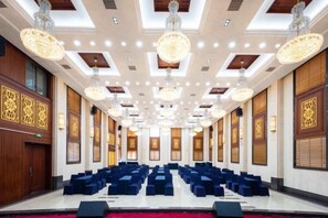 A conference room with rows of blue chairs, chandeliers, and patterned wall panels. - Taohuashan Ecological Garden Hotel (Shishou)