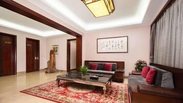A spacious living area with a large coffee table, a sofa, and a red patterned rug.