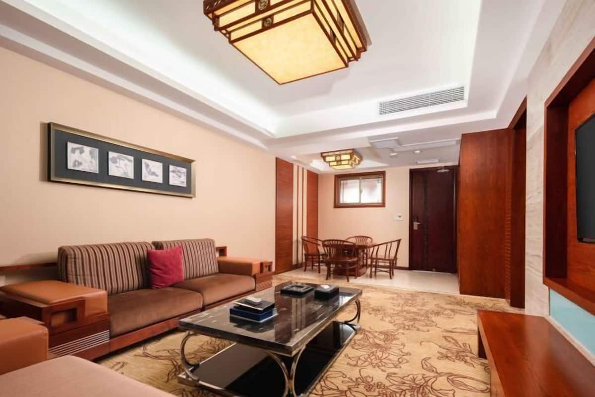 A living room with a sofa, coffee table, framed pictures, and a dining area with chairs and a table.