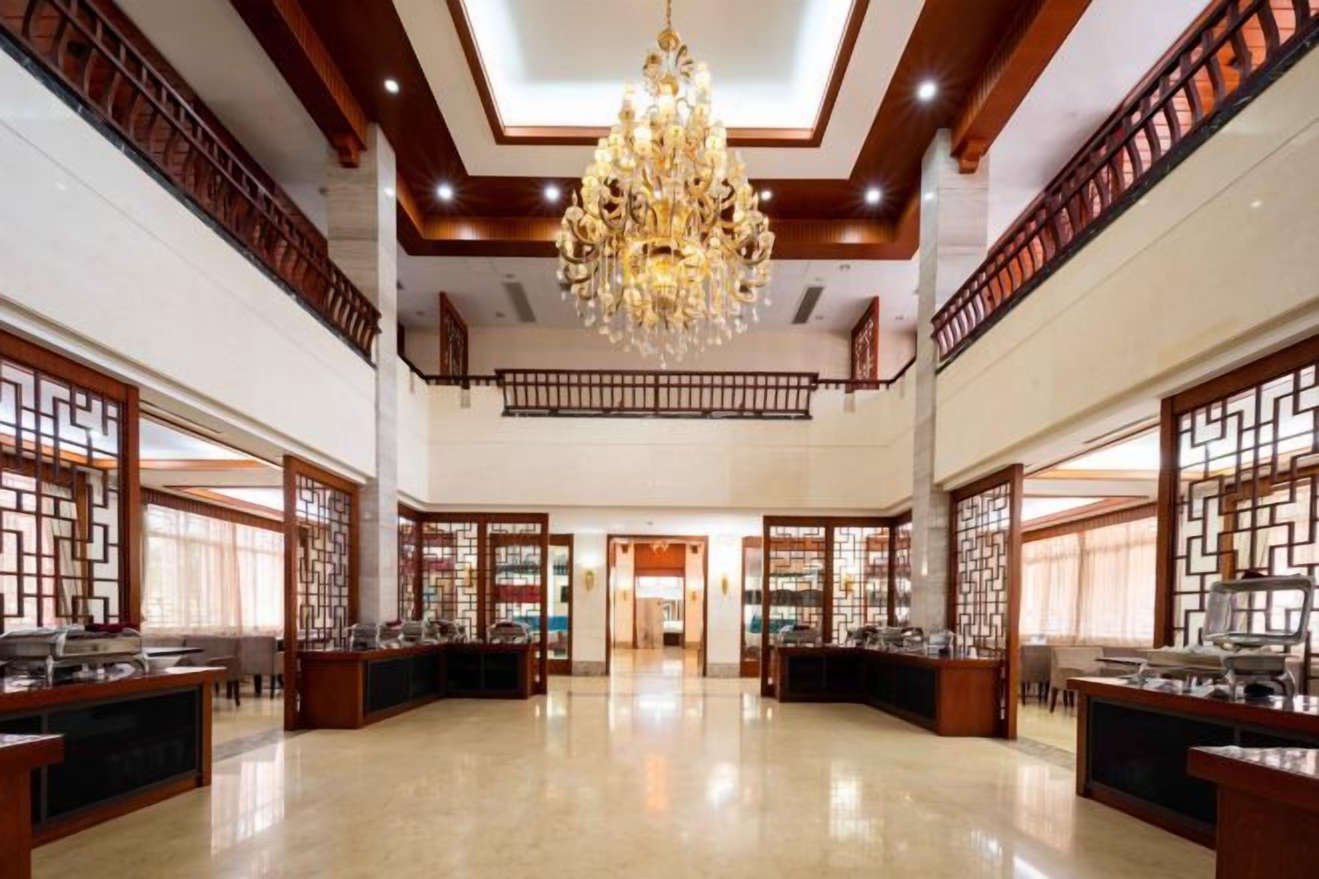 A spacious lobby with a high ceiling, ornate chandeliers, and traditional wooden partitions.