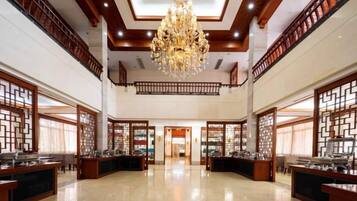 A spacious lobby with a high ceiling, ornate chandeliers, and traditional wooden partitions.