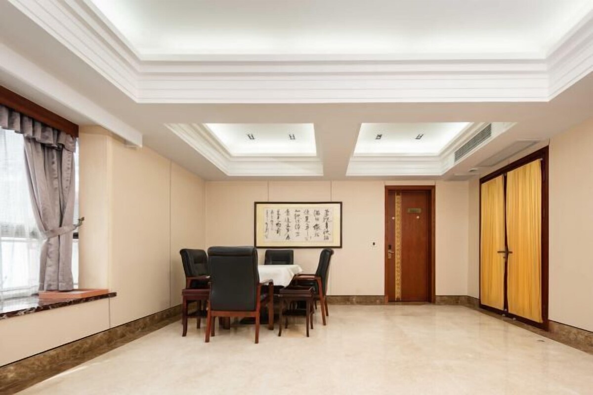 Un salón de conferencias con techo alto, tragaluces, una puerta de madera y una obra de arte enmarcada en la pared.