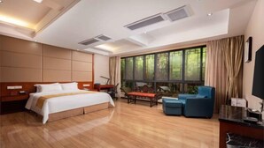 Habitación de hotel con una cama grande, un escritorio con silla, un sofá y una ventana con cortinas.