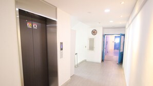 Ein Flur mit Aufzug, einer Wanduhr und einer Tür zu einem weiteren Raum.