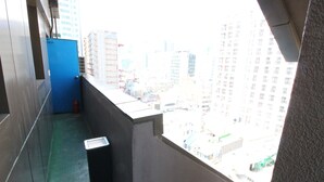 Ein schmaler Balkon mit Blick auf eine Stadtlandschaft.