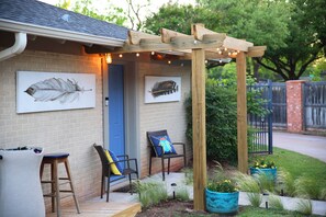 A house with a wooden pergola, two chairs with cushions, and a blue door. - The Sylvan Suite by Curated Stays: Queen Bed (Abilene)
