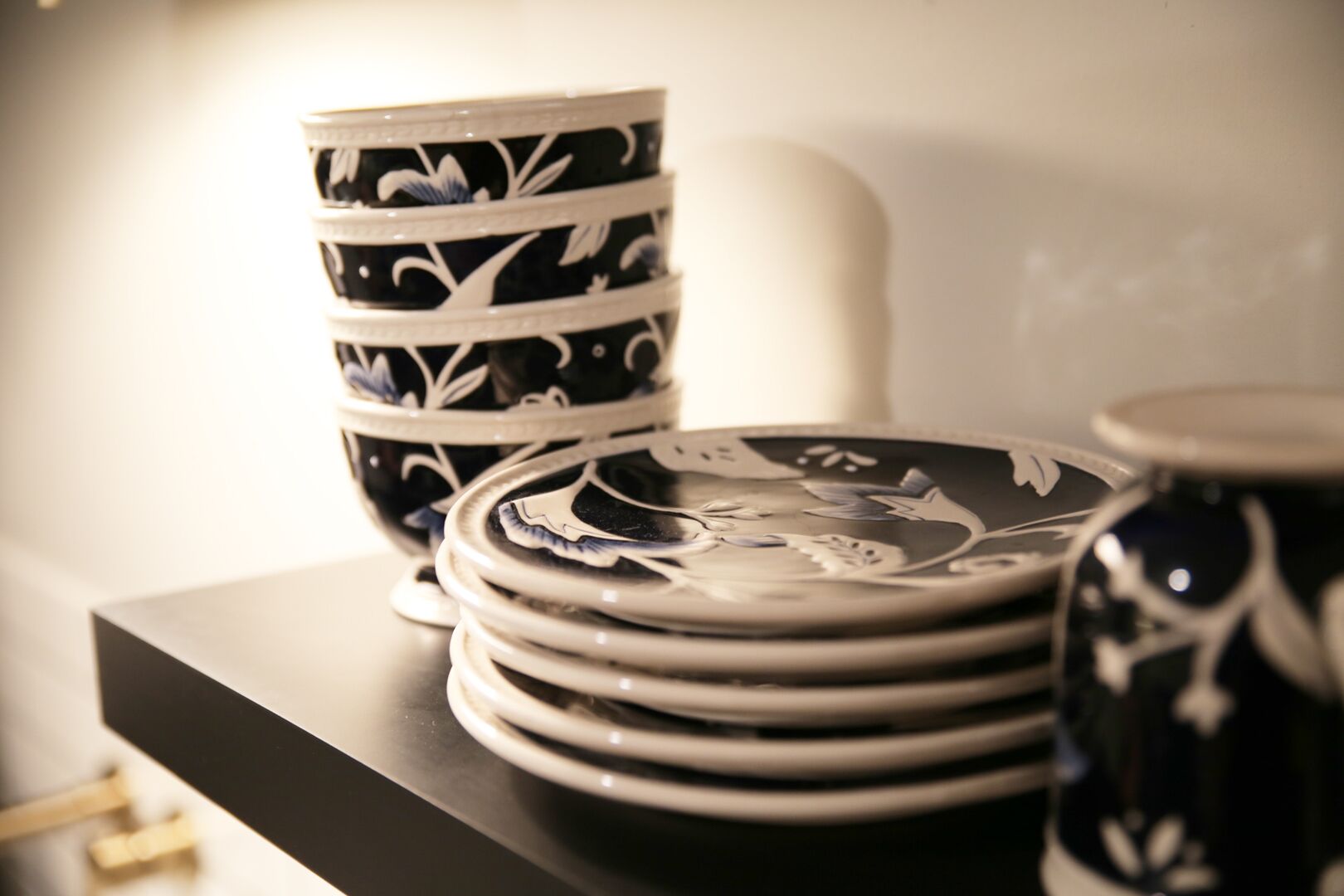 A stack of black and white patterned plates and a matching cup on a dark surface.