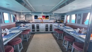 A ship's dining area with multiple tables, bar stools, and a central bar area. - Diving Cruise – Sharm El Sheikh (Egypt Marine Sports Club)
