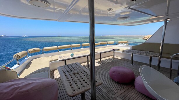 A deck with seating, a table, and a view of the ocean. - Diving Cruise – Sharm El Sheikh (Egypt Marine Sports Club)