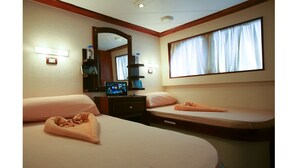 A hotel room with two beds, a TV, a mirror, and a window with curtains. - Diving Cruise – Sharm El Sheikh (Egypt Marine Sports Club)