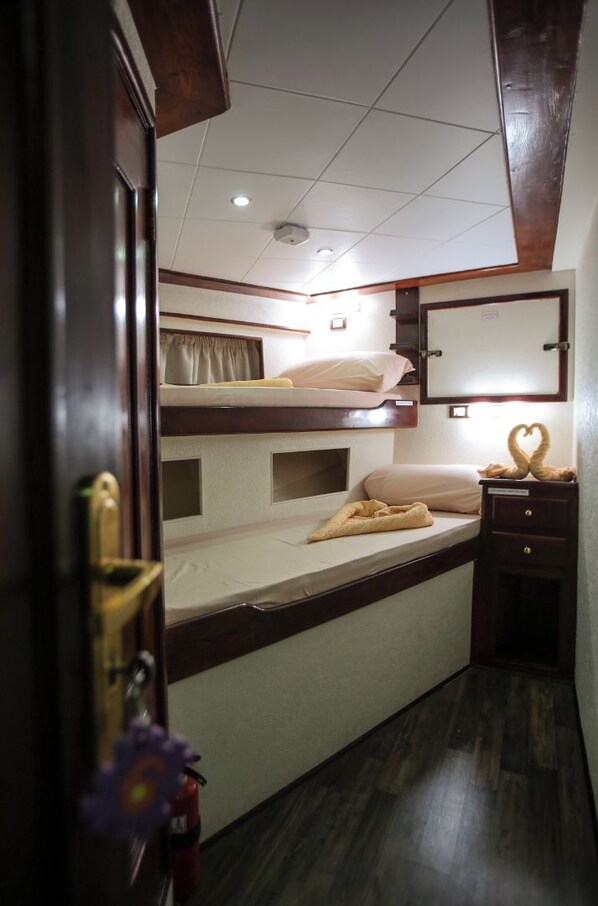 A compact cabin with bunk beds, a small bedside table, and a mirror.