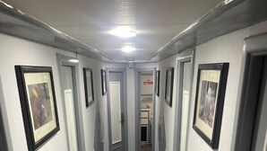 A narrow hallway with doors on both sides, each with a framed picture above. The floor has a patterned tile design. - Diving Cruise – Sharm El Sheikh (Egypt Marine Sports Club)