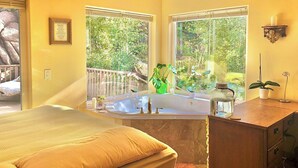 A bedroom with a large bed, a bathtub, and a wooden dresser. - Heaven on Earth Retreat's Spectacular Suite in Prescott's Gorgeous Granite Dells (Prescott)