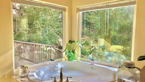 A bathroom with a large bathtub, two windows with blinds, a wooden deck outside, and a potted plant on the windowsill. - Heaven on Earth Retreat's Spectacular Suite in Prescott's Gorgeous Granite Dells (Prescott)