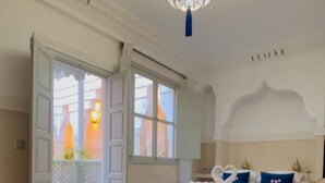 A hotel room with two beds, a chandelier, and a view of the outside. - RIAD MAGNOLIA (Marrakech)