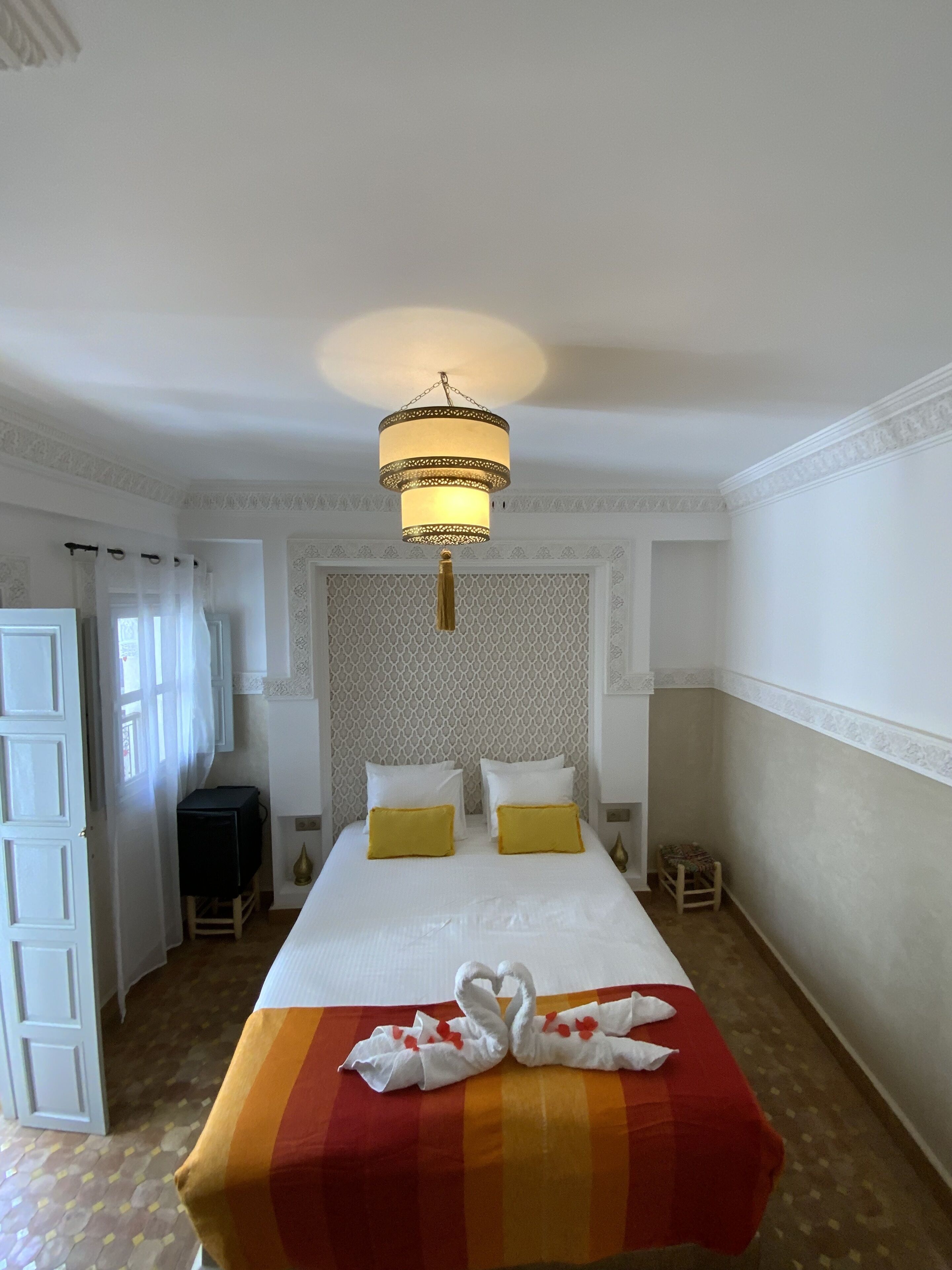 A hotel room with a bed, a chandelier, and a television.