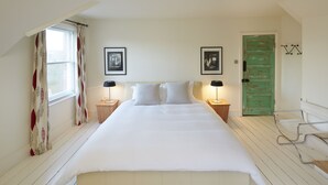 A bedroom with a large bed, two bedside tables with lamps, a green door, and a window with curtains. - Extremely spacious loft located in the vibrant America Ground close to the beach (Hastings)