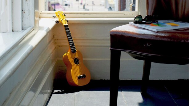 A room with a window, a chair, and a guitar leaning against the window sill. - Extremely spacious loft located in the vibrant America Ground close to the beach (Hastings)