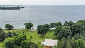 A house with a large lawn and a view of the water. - Relaxing Lake Waterfront Home (Simcoe Island, Frontenac Islands)