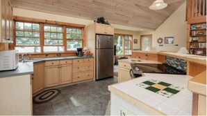 A kitchen with wooden cabinets, a stainless steel refrigerator, and a large window. - Relaxing Lake Waterfront Home (Simcoe Island, Frontenac Islands)