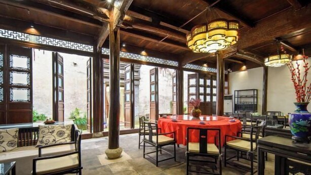 A traditional-style dining area with round tables, wooden beams, and decorative lanterns. - Hanqing Hostel (Deqing)