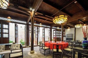 A traditional-style dining area with round tables, wooden beams, and decorative lanterns. - Hanqing Hostel (Deqing)
