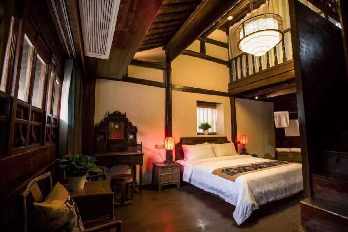 Una habitación tradicional con cama, mesita de noche, lámpara y lámpara colgante.