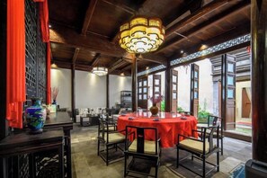 A traditional dining area with a round table, chairs, and a hanging light fixture. - Hanqing Hostel (Deqing)