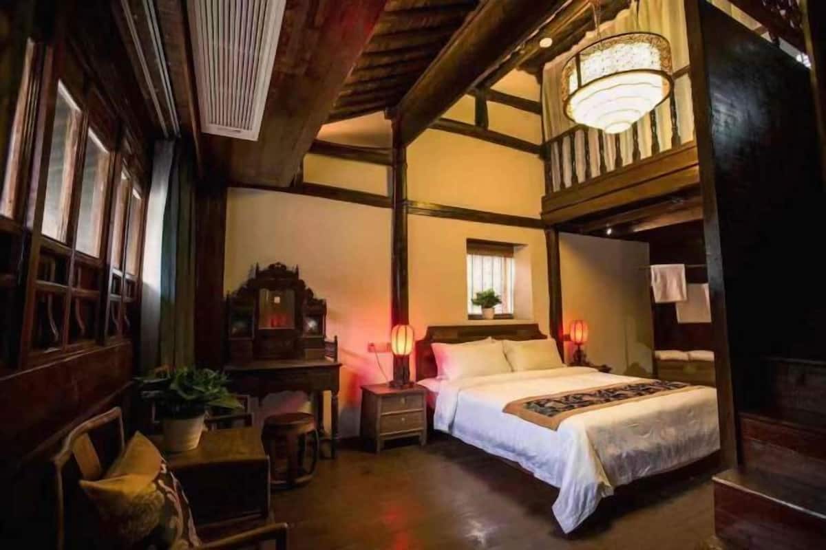 Una habitación tradicional con cama, mesitas de noche, escritorio y una silla.