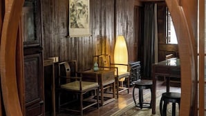 A traditional wooden room with a table, chairs, and a lamp. - Hanqing Hostel (Deqing)