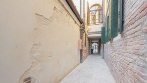 Une ruelle étroite, avec un mur de briques sur la droite et un mur enduit de plâtre sur la gauche.