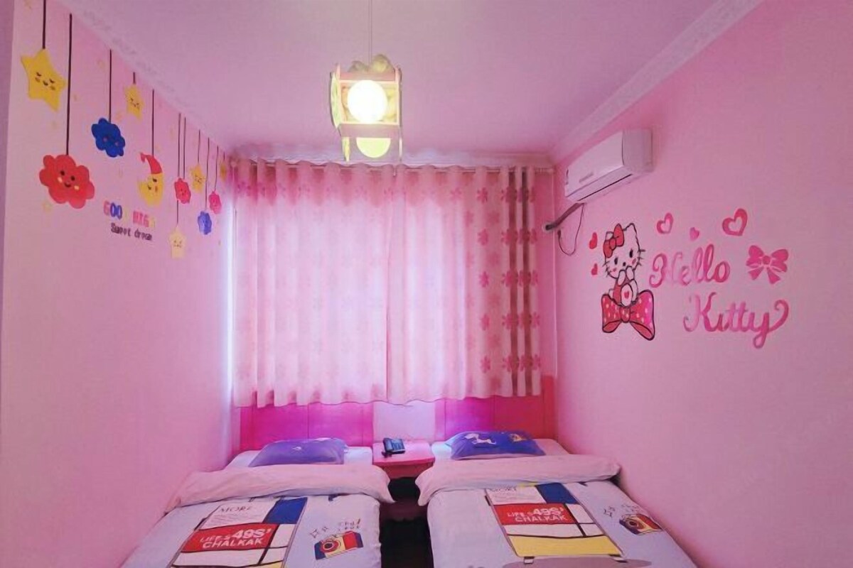 Ein zartrosa Schlafzimmer mit zwei Betten, einem Fenster mit rosa Vorhängen und Wanddekorationen, darunter ein Hello Kitty Schild.