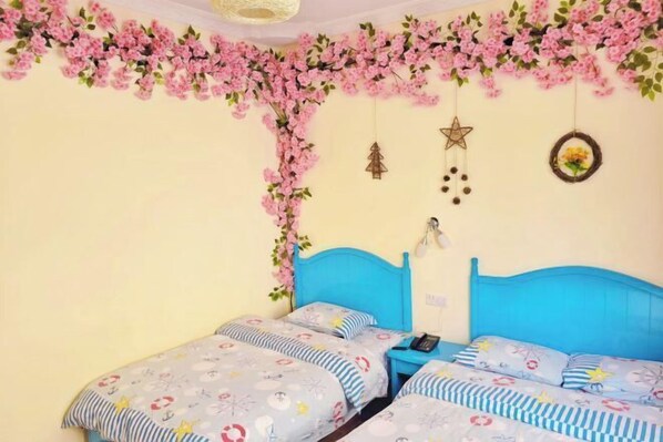 Ein Schlafzimmer mit zwei Betten, einer blauen Kopfteil und rosa floralen Wanddekorationen.