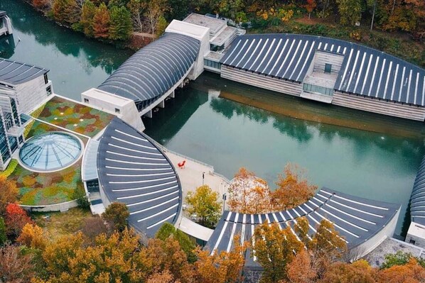 A modern building with a circular roof structure, a central courtyard, and a body of water.
