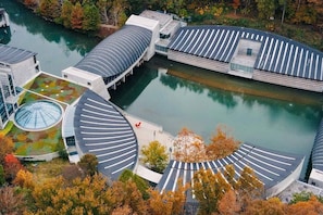 Un edificio moderno con una estructura de techo circular, un patio central y una masa de agua.