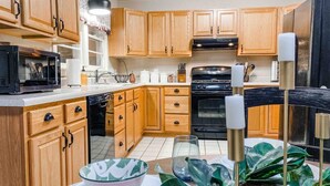 A kitchen with wooden cabinets, a microwave, oven, and a sink. There are plants and candles on the counter.