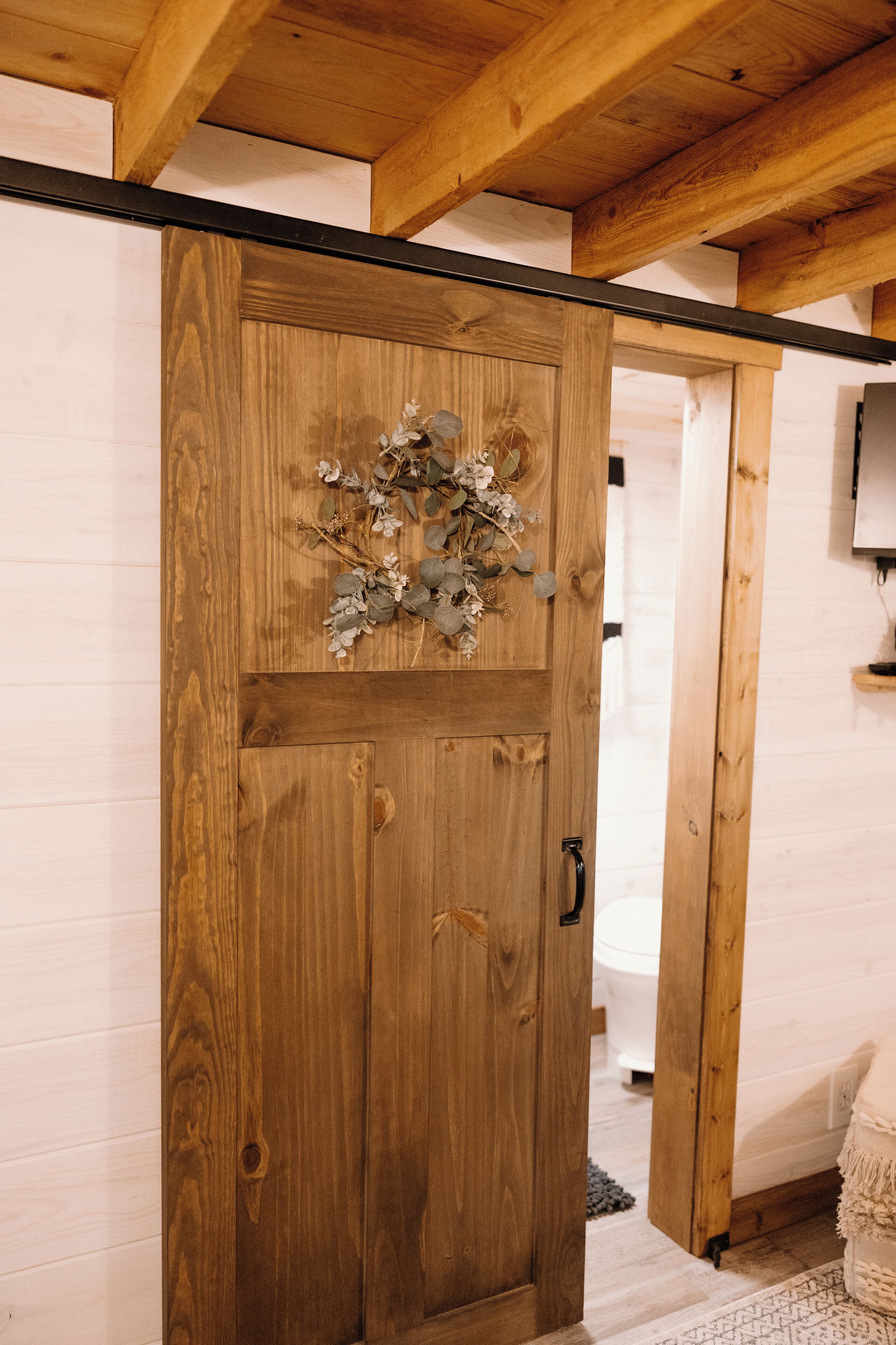 A wooden door with a decorative wreath, a visible handle, and a sliding mechanism.