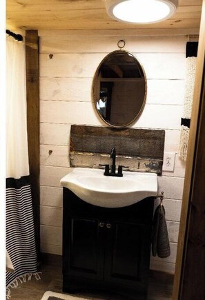 A bathroom with a white sink, a wooden vanity, a mirror, and a towel hanging on the wall.