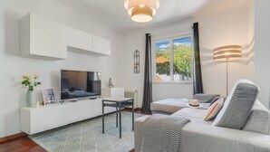 A modern living room with a flat-screen TV, a sofa, a coffee table, and a window with curtains. - Yellow Rose by Atlantic Holiday (Funchal)