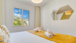 A hotel room with a bed, a window with a view of greenery, and a unique geometric light fixture. - Yellow Rose by Atlantic Holiday (Funchal)