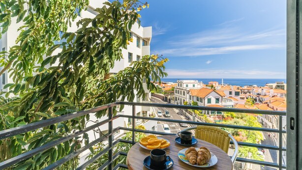 A balcony with a table set for breakfast, overlooking a coastal town. - Yellow Rose by Atlantic Holiday (Funchal)