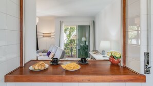 A hotel room with a wooden counter, breakfast items, a laptop, and a view of the outdoor area. - Yellow Rose by Atlantic Holiday (Funchal)